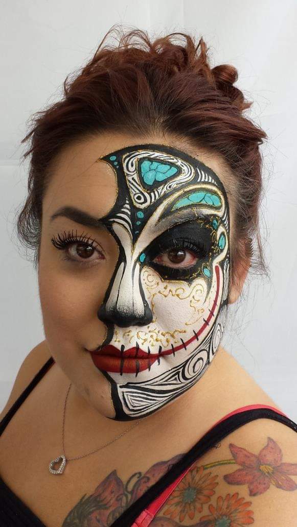 Brunette woman with the right side of her face  painted to resemble a skull with lots of flowing detailed paint on it
